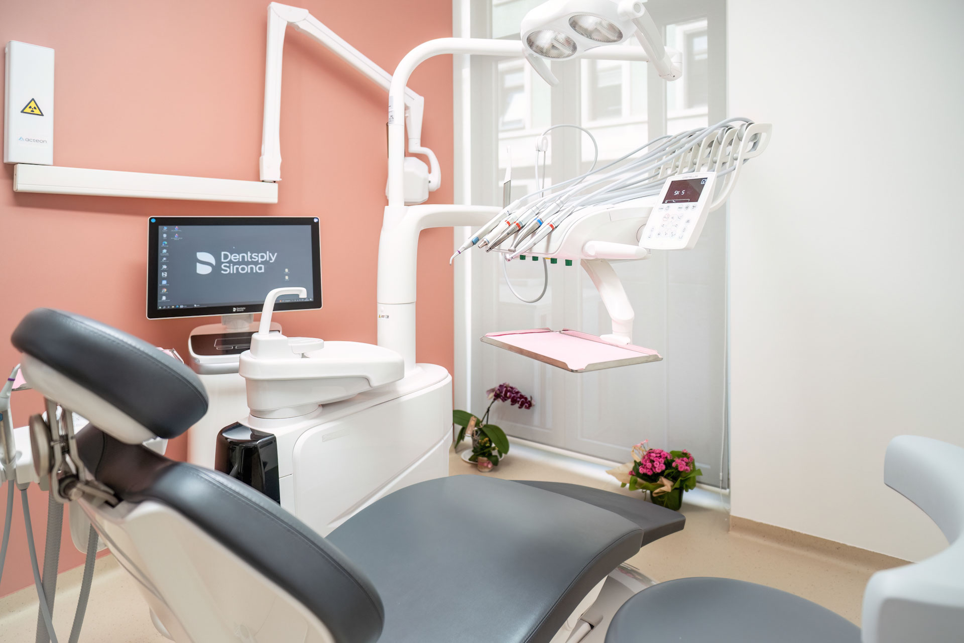 Foto della sala per con poltrona e attrezzi dentistici con muro rosa